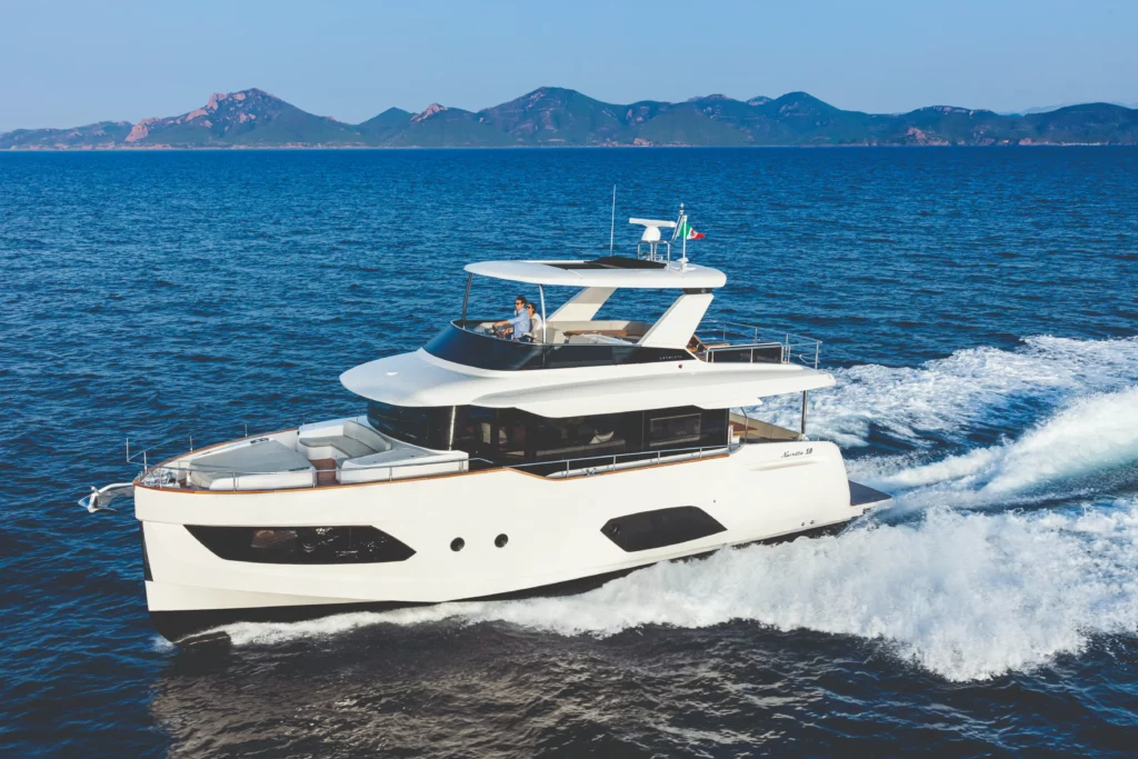 Luxe motorjacht Absolute Navetta 58 vaart op zee met een bergachtige horizon op de achtergrond.