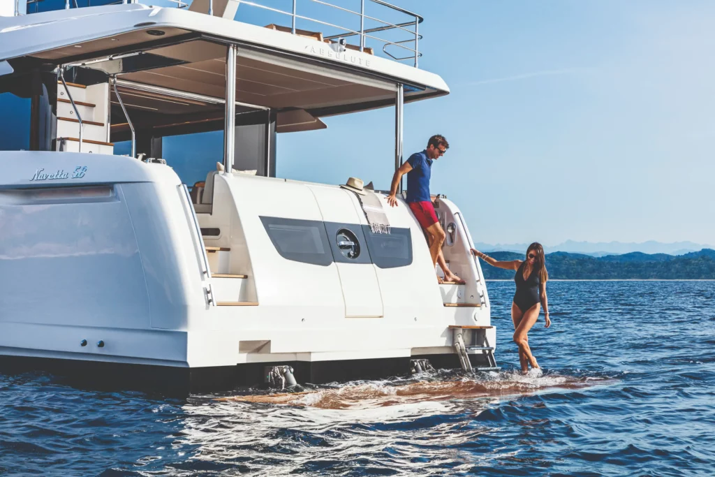 Twee mensen genieten van een zonnige dag op het water vanaf de achtersteven van de luxe jacht Absolute Navetta 58.