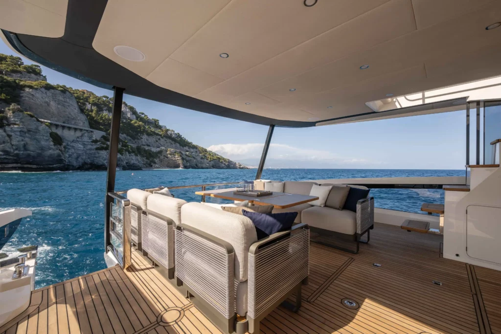 Het achterdek van het luxe jacht Absolute Navetta 58'' biedt een rustig uitzicht op zee en rotsachtige kustlijnen.
