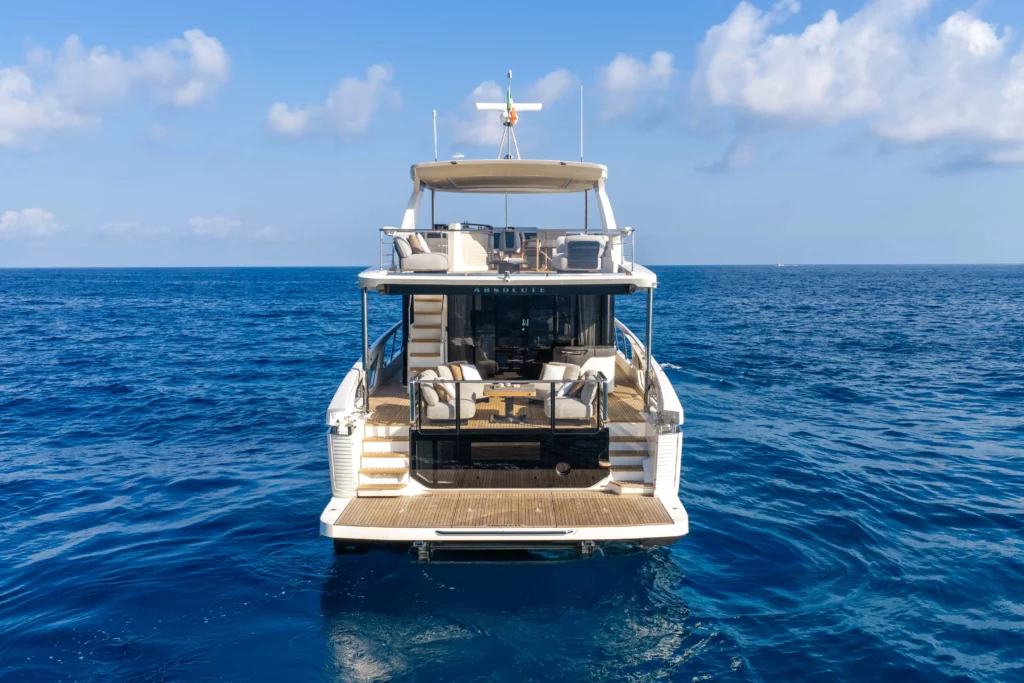 Achteraanzicht van de luxe jacht Absolute Navetta 66 op open zee onder een heldere blauwe hemel.