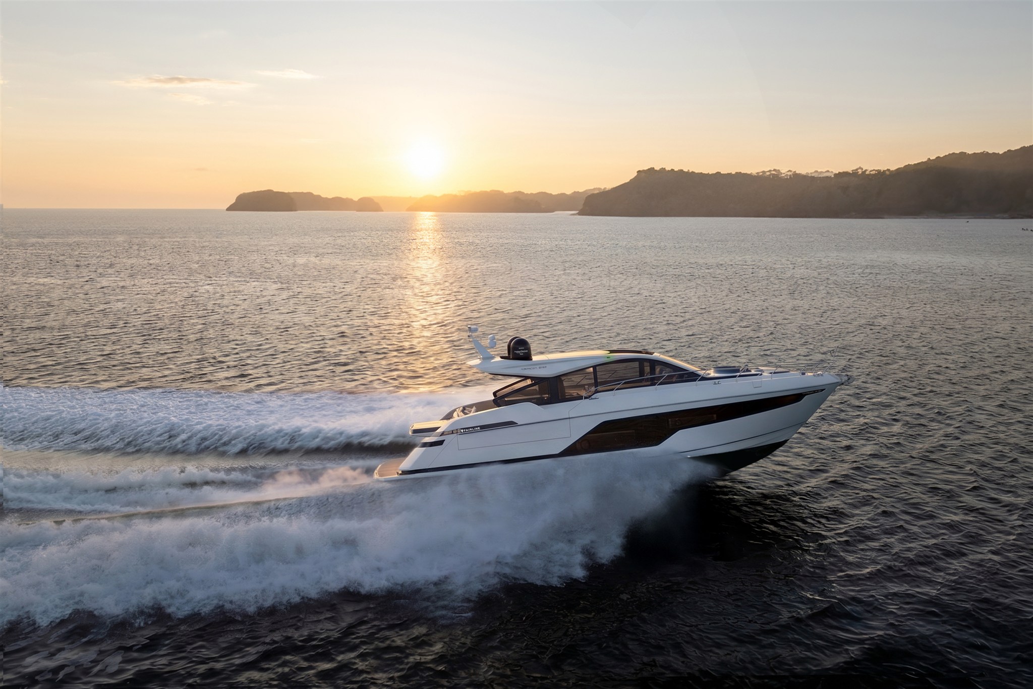 Zijaanzicht van een Fairline Targa 58 GTO die over het water vaart bij zonsondergang.