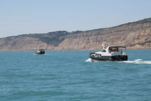 Twee motorboten varen langs de rotsachtige kust van de Engelse Zuidkust tijdens de Jonkers Toertocht 2015.