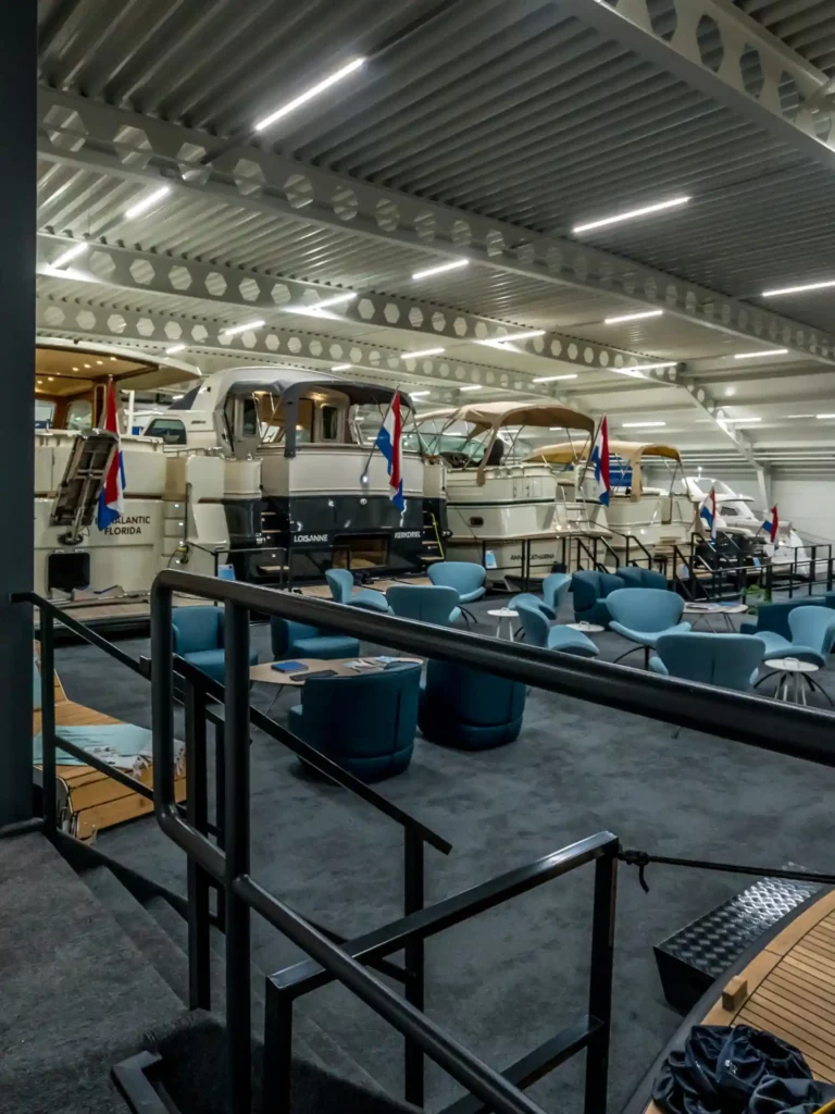 Showroom van Jonkers Yachts met luxe jachten en moderne zithoeken in een overdekte hal.