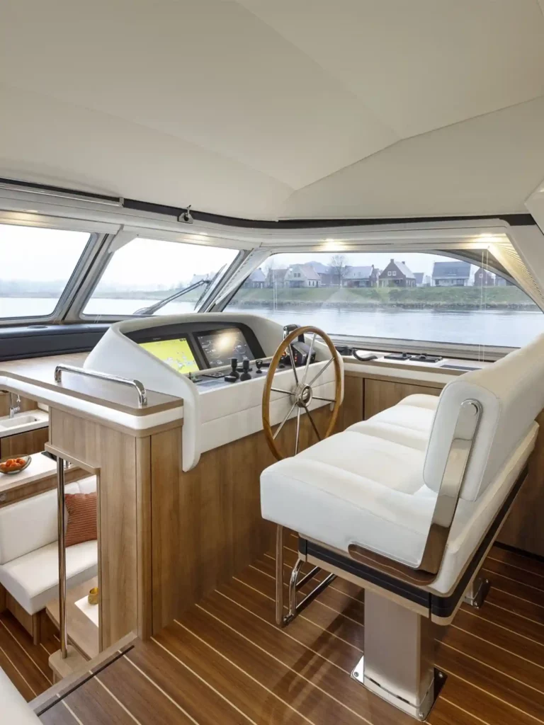Luxe interieur van een Linssen-jacht met houten afwerking, stuurstand en panoramisch uitzicht op het water.